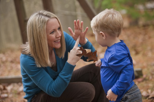 woman using american sign language signs with young child