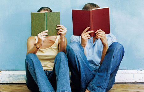 Two people sitting next to each other, with books covering their faces