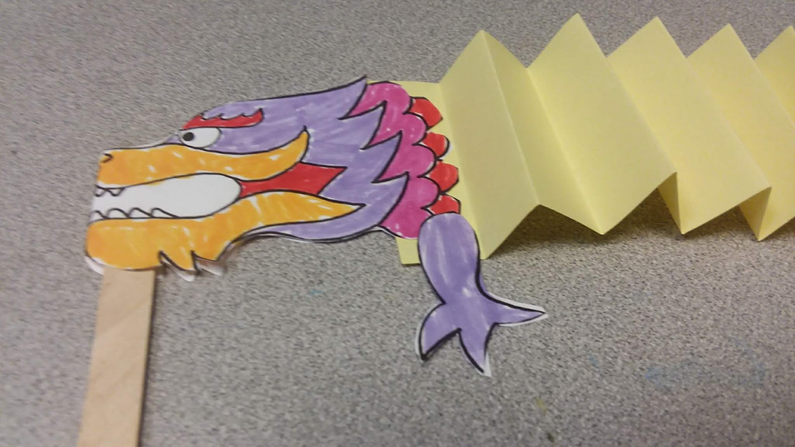 A paper Chinese Dragon puppet attached to a craft stick