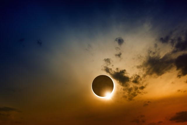 Solar Eclipse with dramatic dark blue and orange sky background