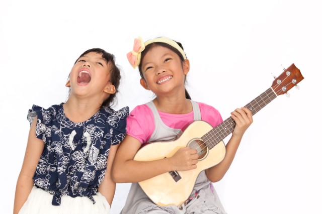 Girl sings next to girl playing guitar.