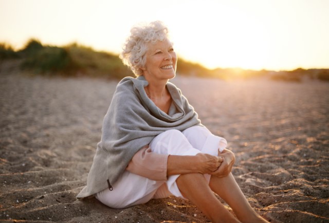 Elderly woman sitting on the beach.