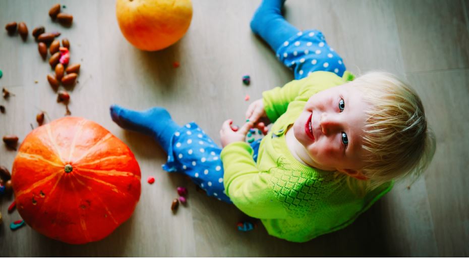 Toddler sitting with pumpkins.