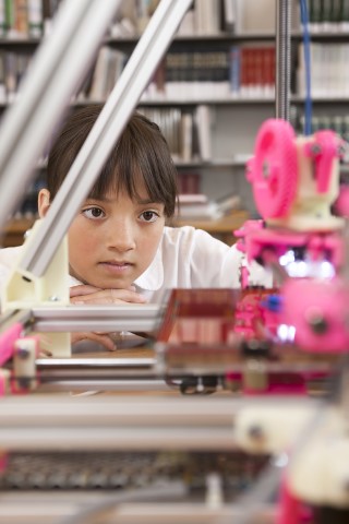A girl watching a 3D printer operate