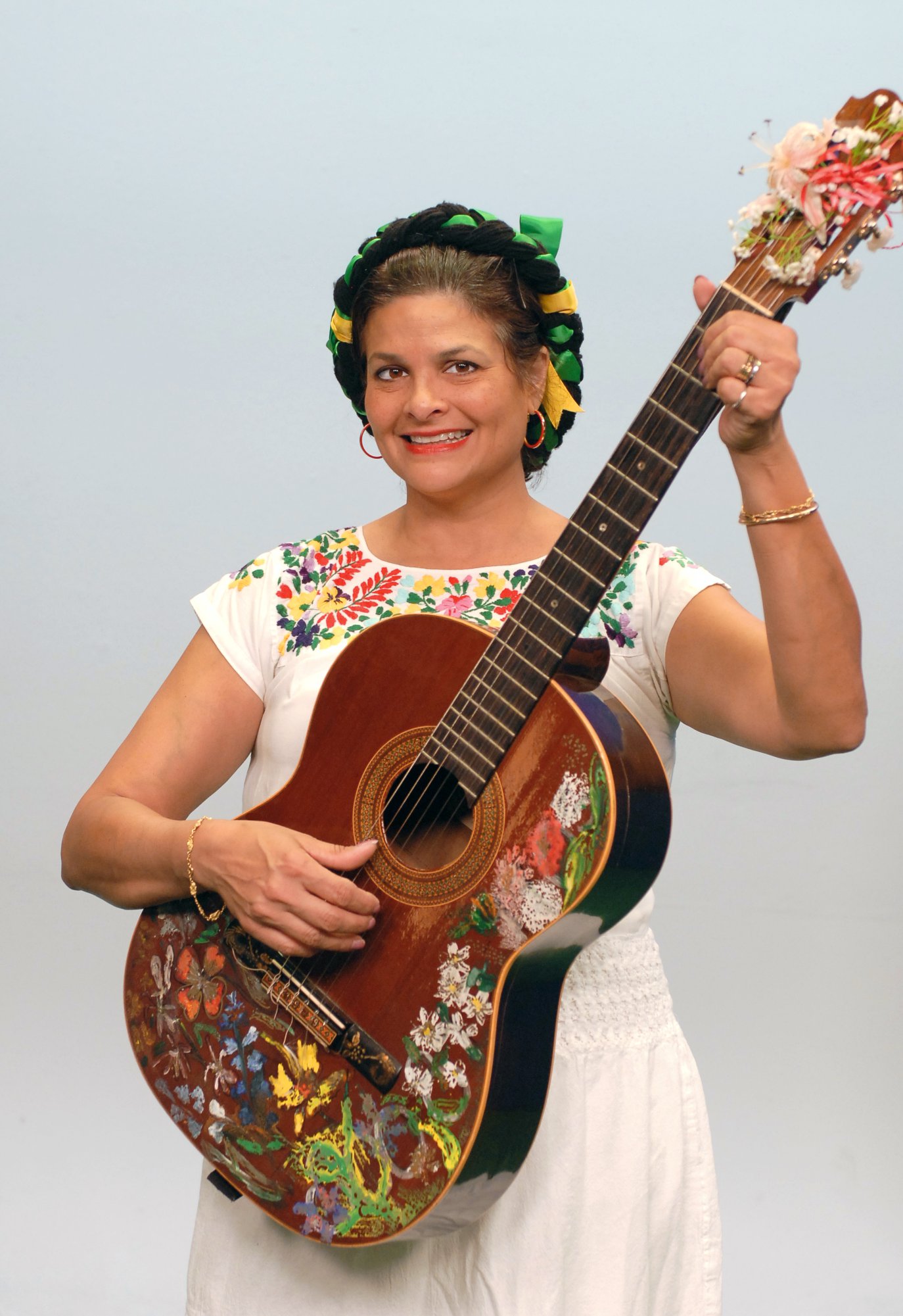 A photo of Georgette Baker in traditional Mexican garb while holding a guitar
