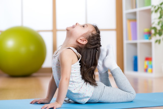 Girl doing a yoga pose on mat.