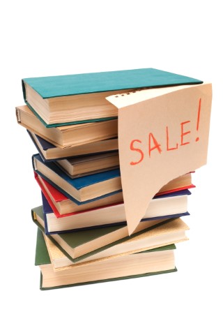 A pile of books with a "sale" sign