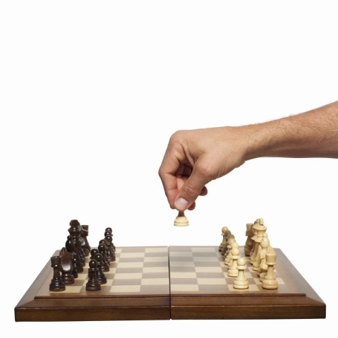 Hand moving a chess piece on board.