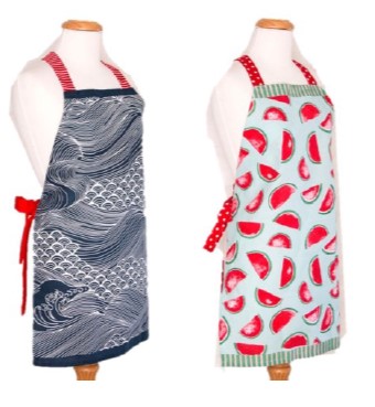 Two aprons displayed on mannequins, one designed in navy blue waves and one in watermelon. 