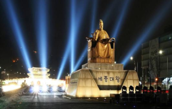 Lights illuminating the sky behind a statue of Korea's King Sejong the Great