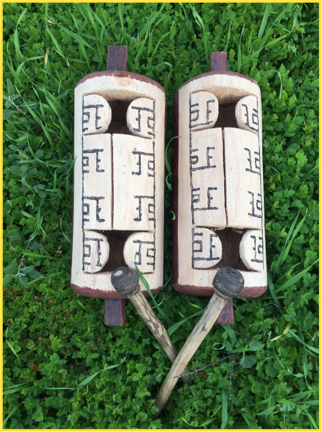 Two carved wooden drums on grass background
