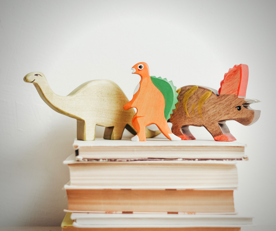 wooden dinosaurs on a stack of books