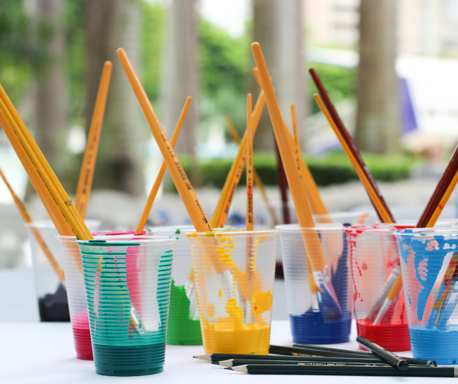 paintbrushes in cups of paint