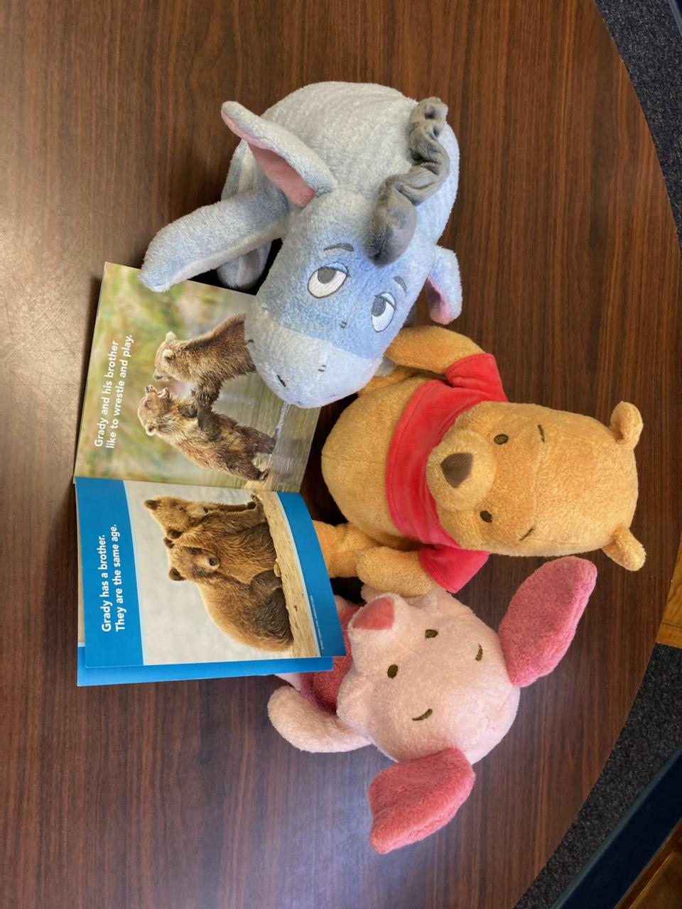 Pooh and Piglet and Eeyore reading about bear cubs