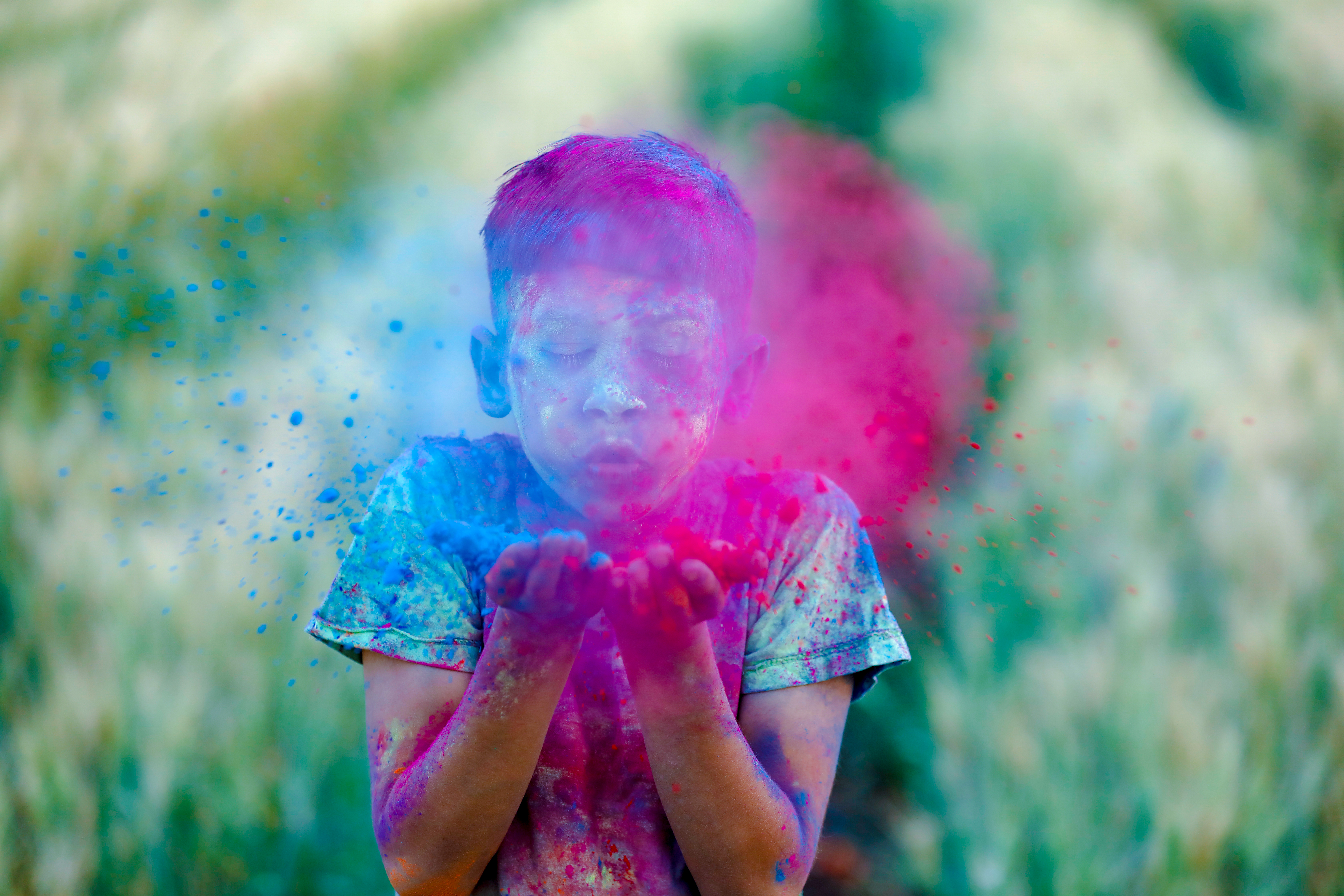 Boy in T-Shirt blowing blue and pink colored powder