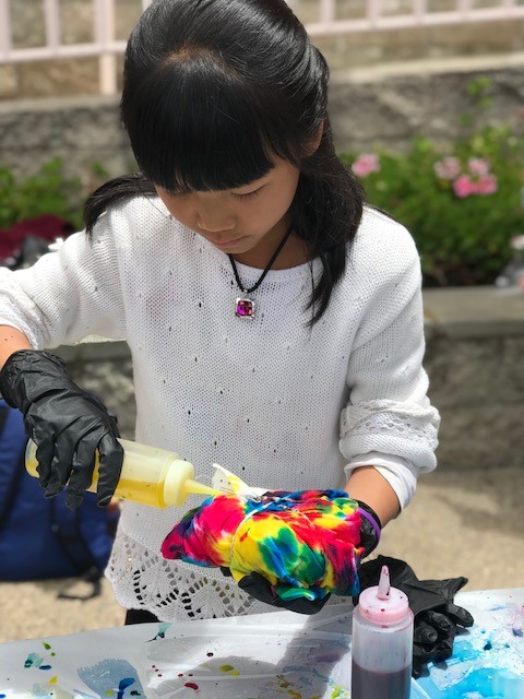 Young girl in white sweater tie-dying a tshirt
