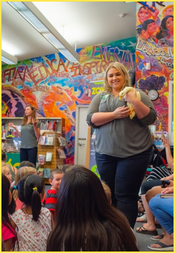 Female presenter showing a duck to children in the library