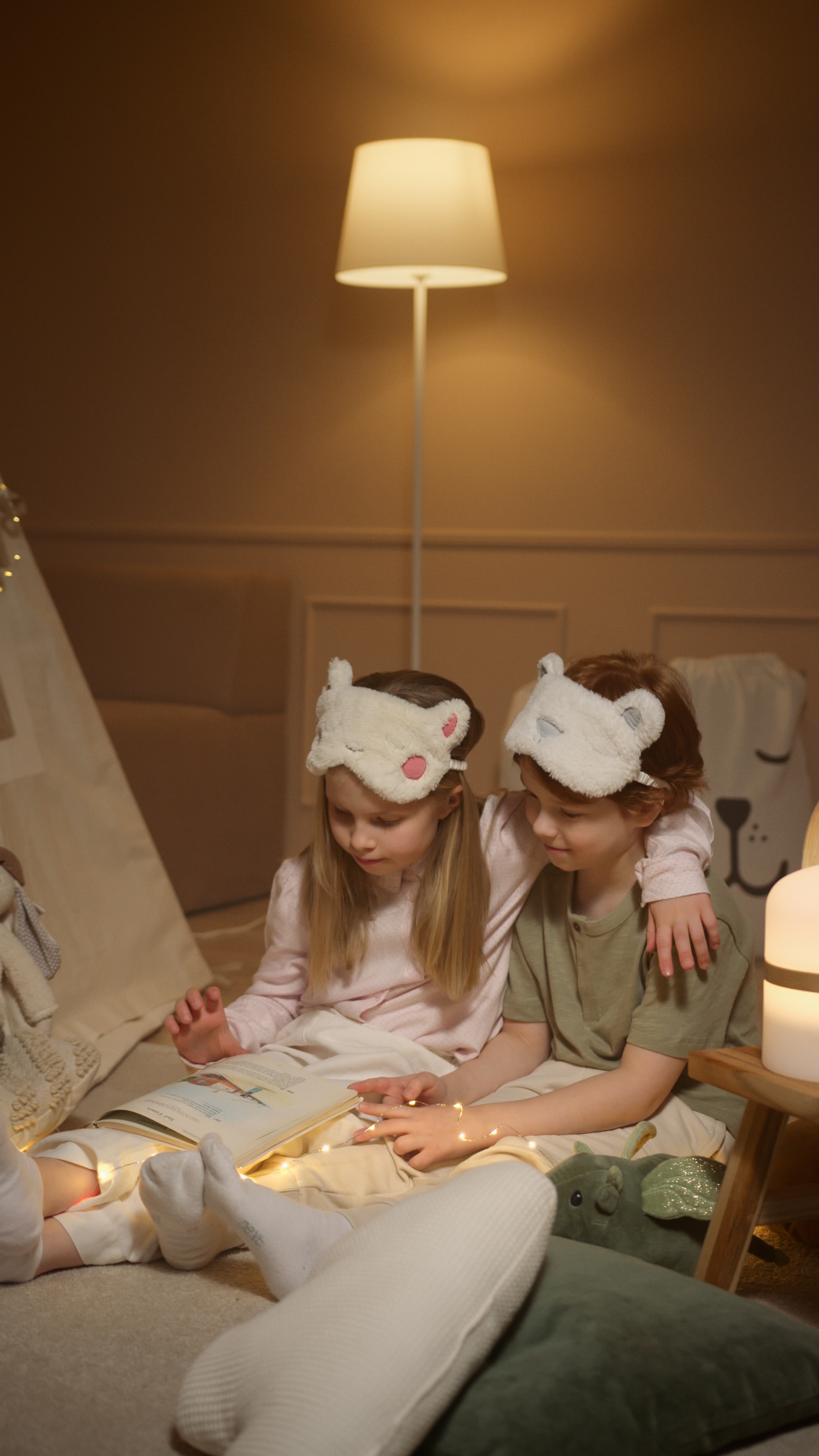 Two children reading a book in their pajamas. 