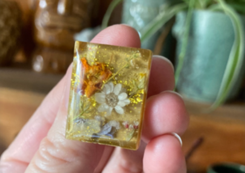 Image of a resin jewelry of flowers and plants molded into resin for a necklace. 