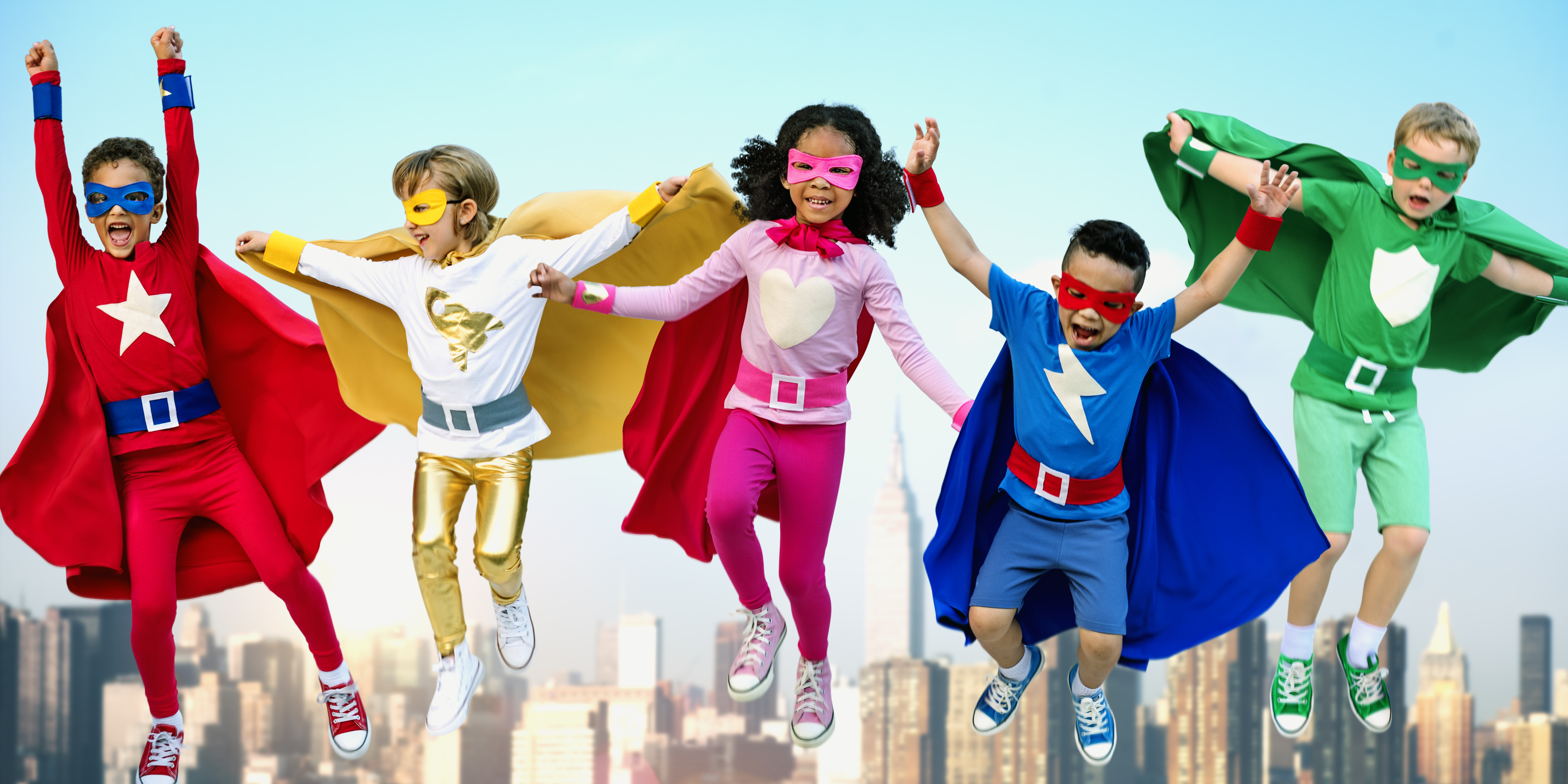 Children dressed as superheroes jump.