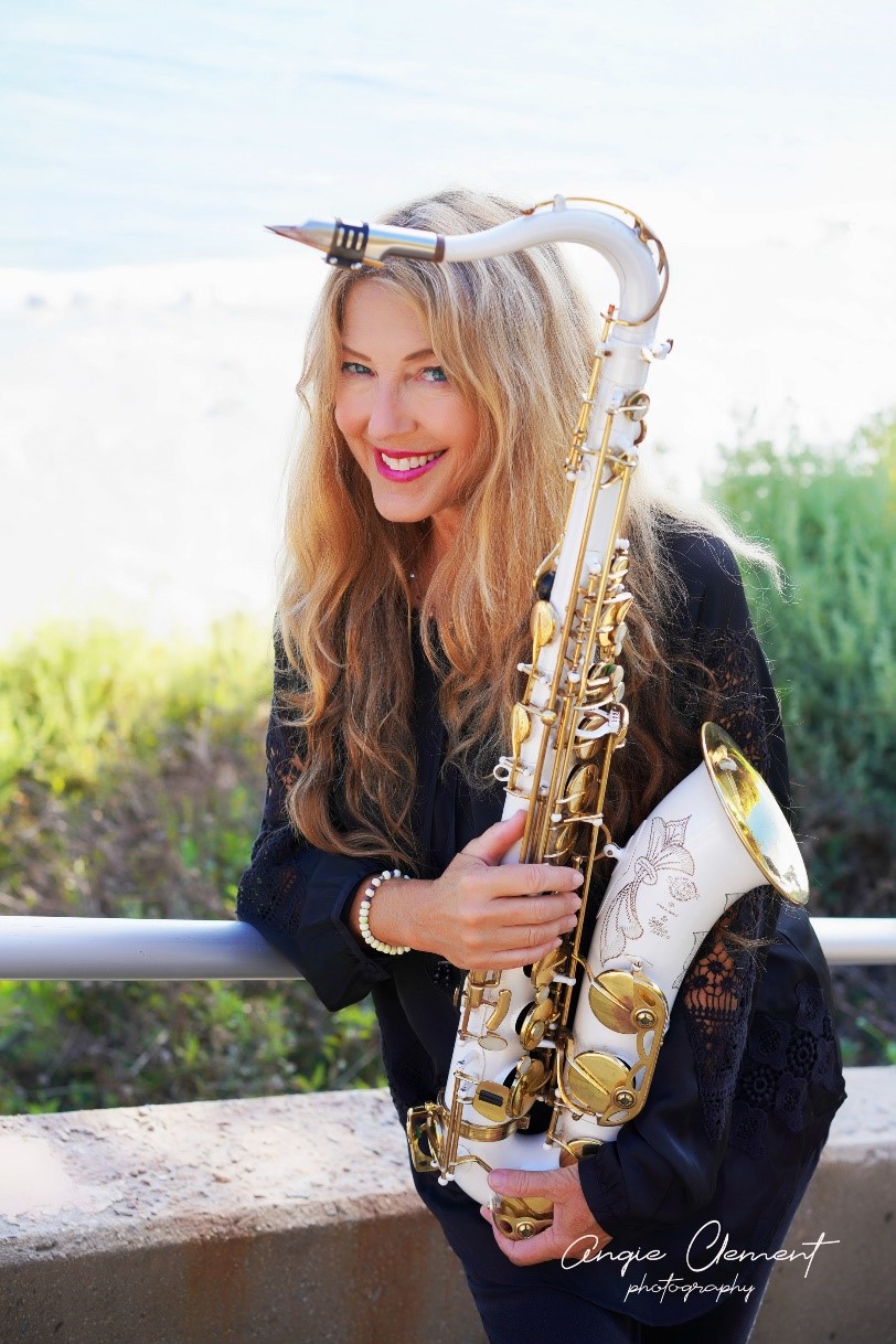Woman dressed in black, holding a white and gold saxophone
