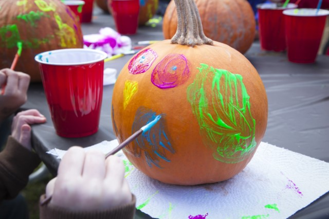The hand of a child painting a pumpkin