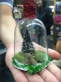 Photo of a light-skinned person's hand holding a handmade bell jar ornament