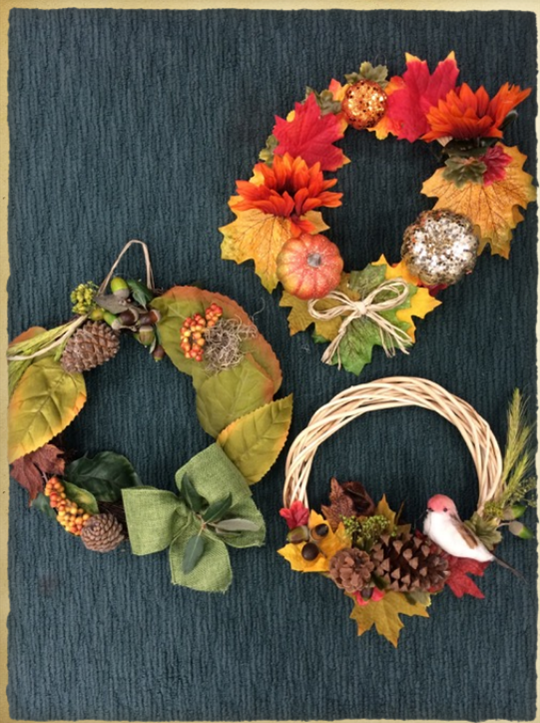 festive wreaths made of blond and brown sticks with squash, yellow and red leaf, and brown pine corn and acorn decorations. 