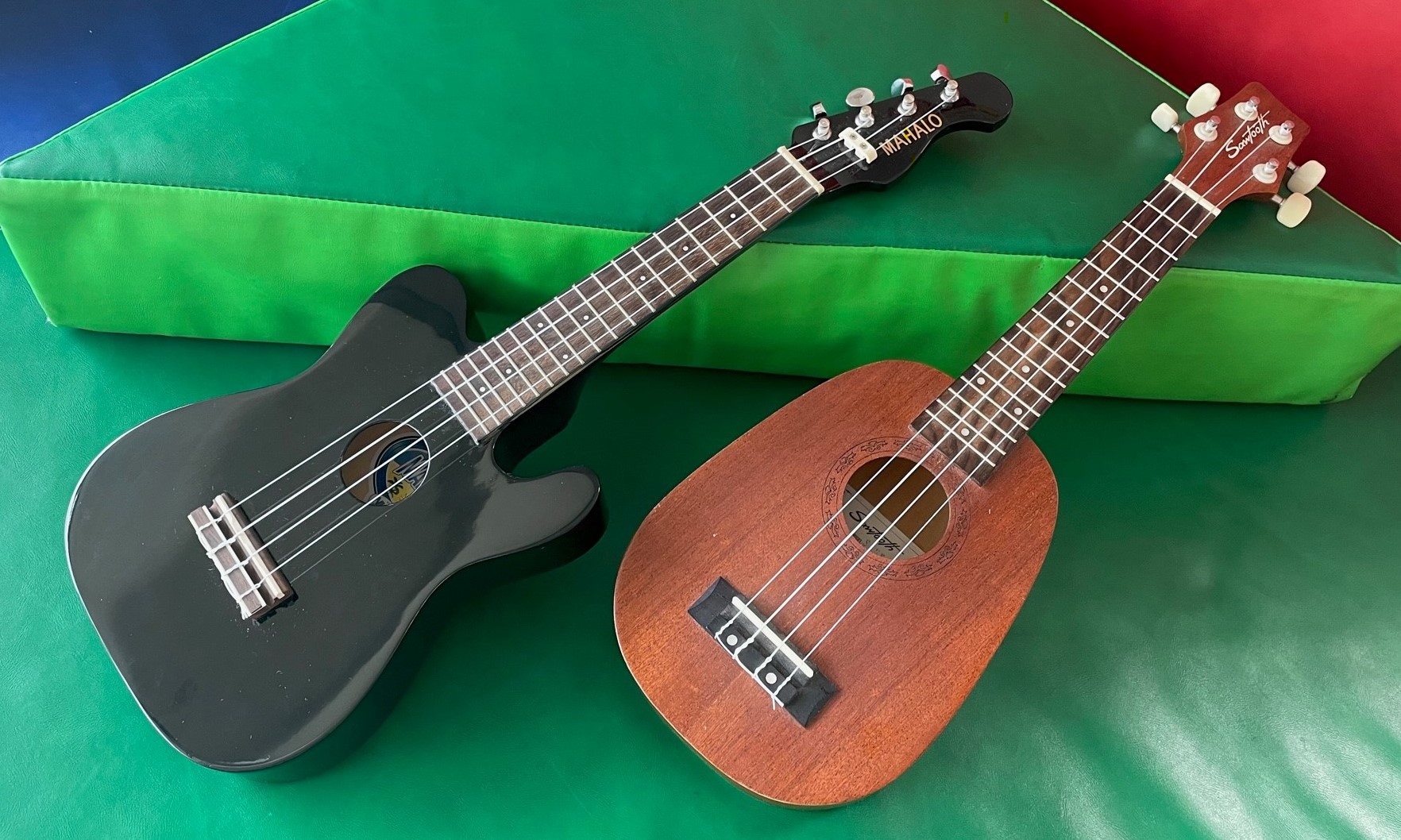 Two ukuleles against a multi-colored background