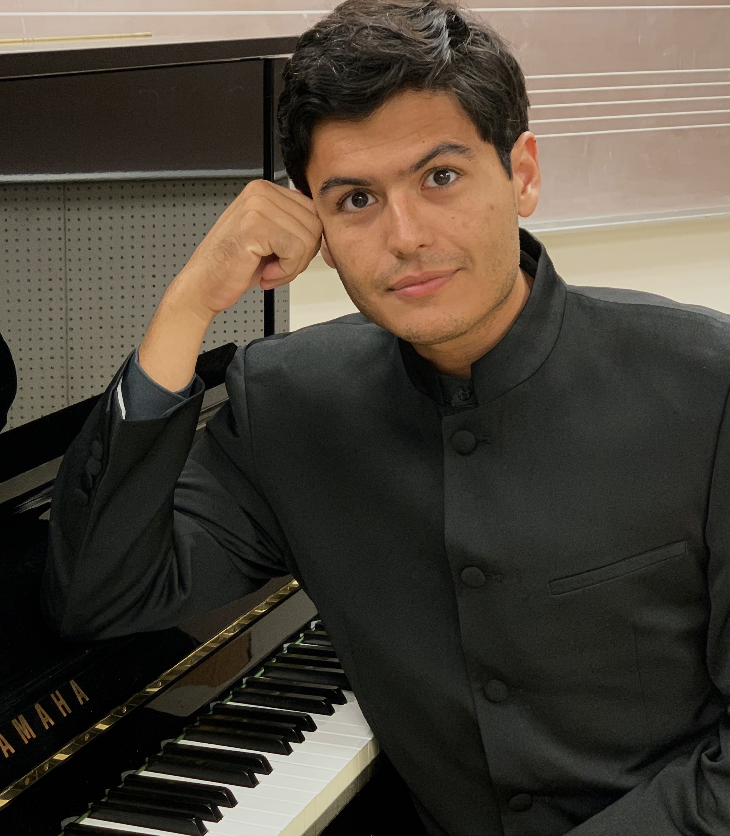 Photo of musician Diego Guerra leaning on a piano