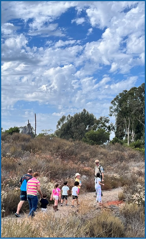 Park Ranger leading families on a trail walk on a sunny day. 