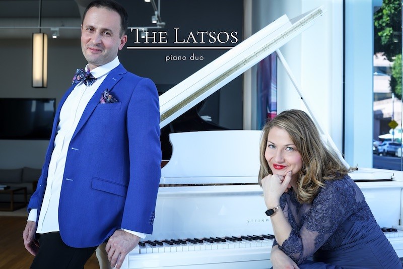 The Latsos standing and sitting at white piano