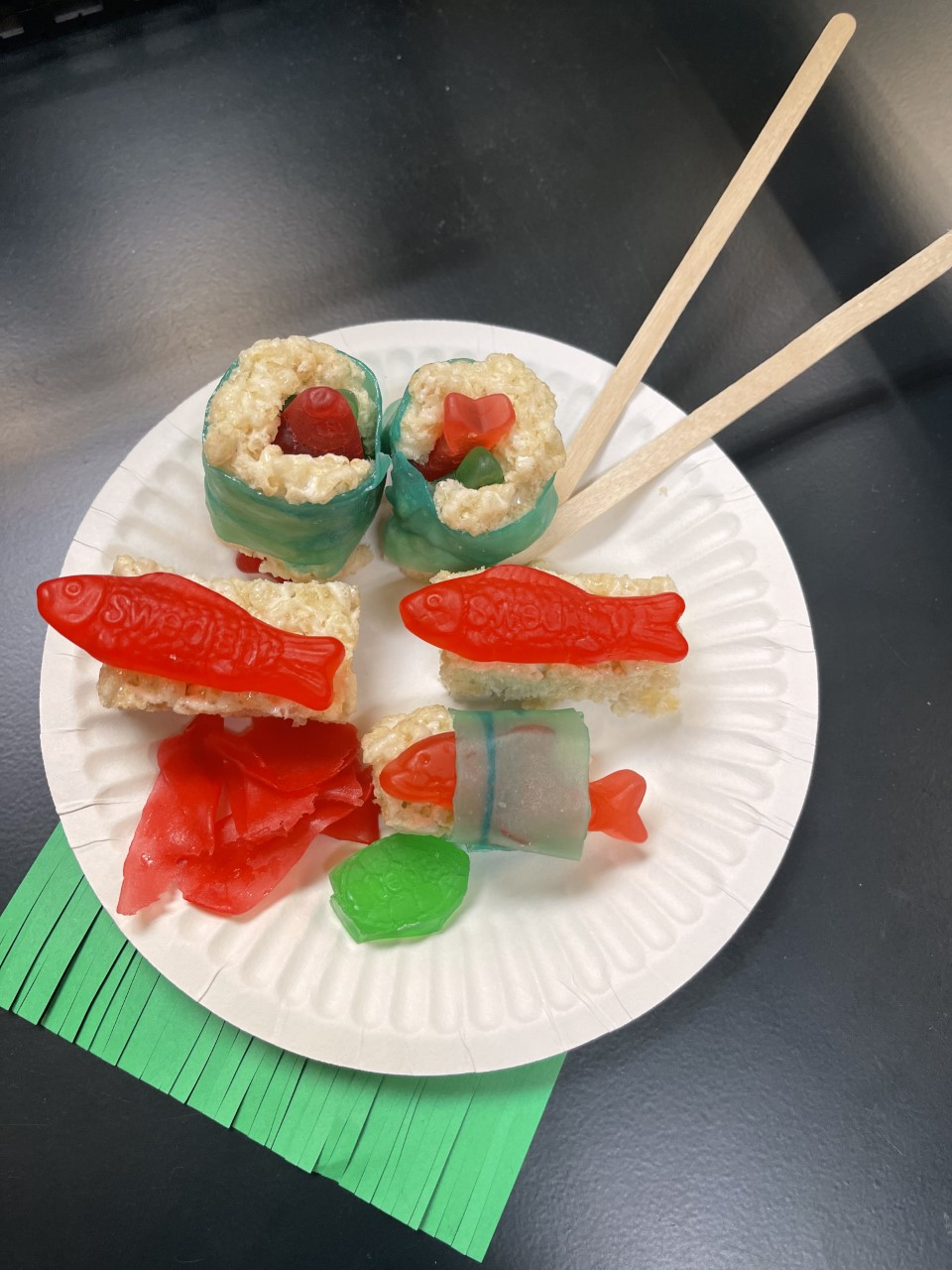 Paper plates with candy assembled to look like sushi with a set of chopsticks