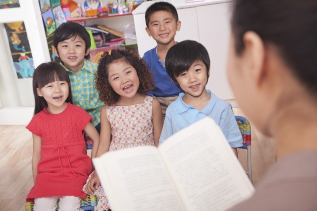 A woman reading to a group of five Chinese children