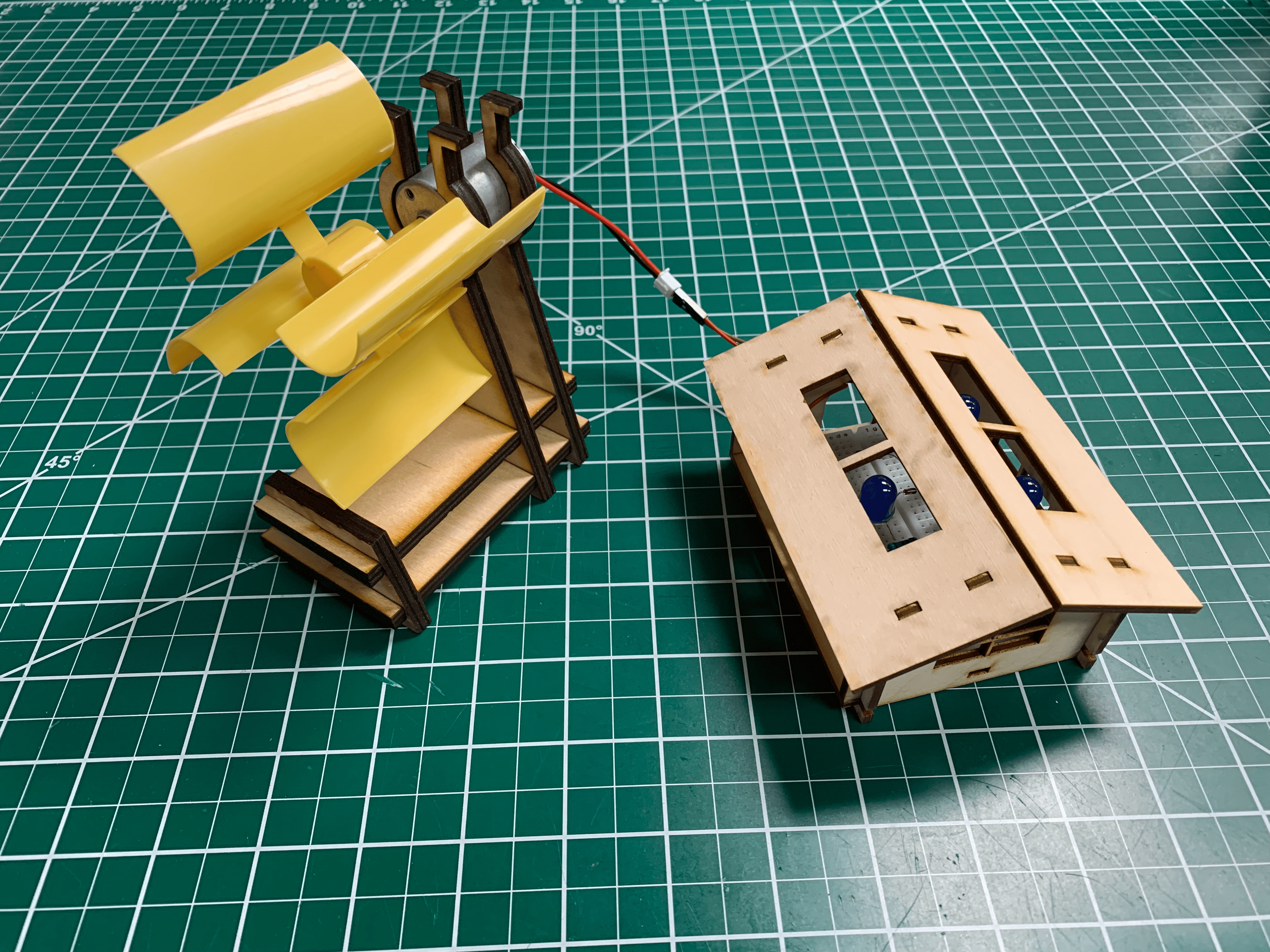 working wood and plastic wind turbine model with breadboard and LEDs in house-shaped wood enclosure