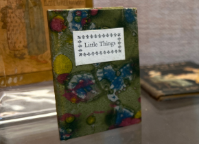 Picture of a miniature book with tile that reads "Little Things."
