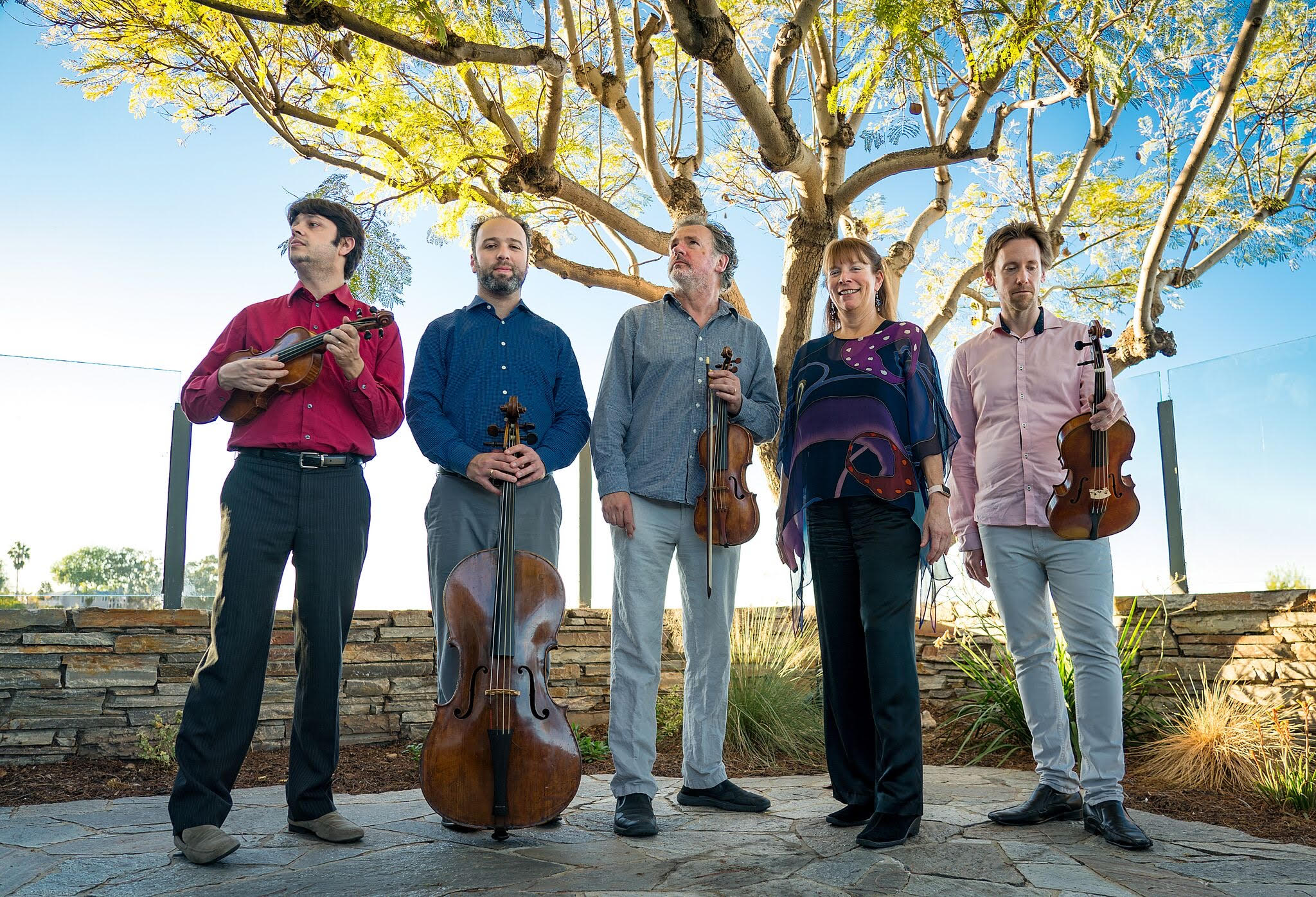 Image of five San Diego Baroque musicians holding instruments, standing outside