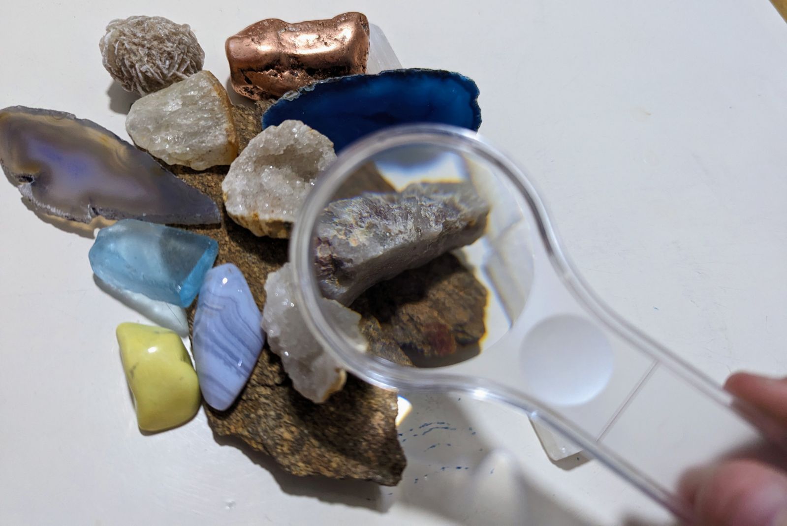 variety of colorful stones and a small handheld magnifying glass