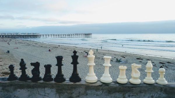 Chess pieces lined up on a wall, with the beach in the background