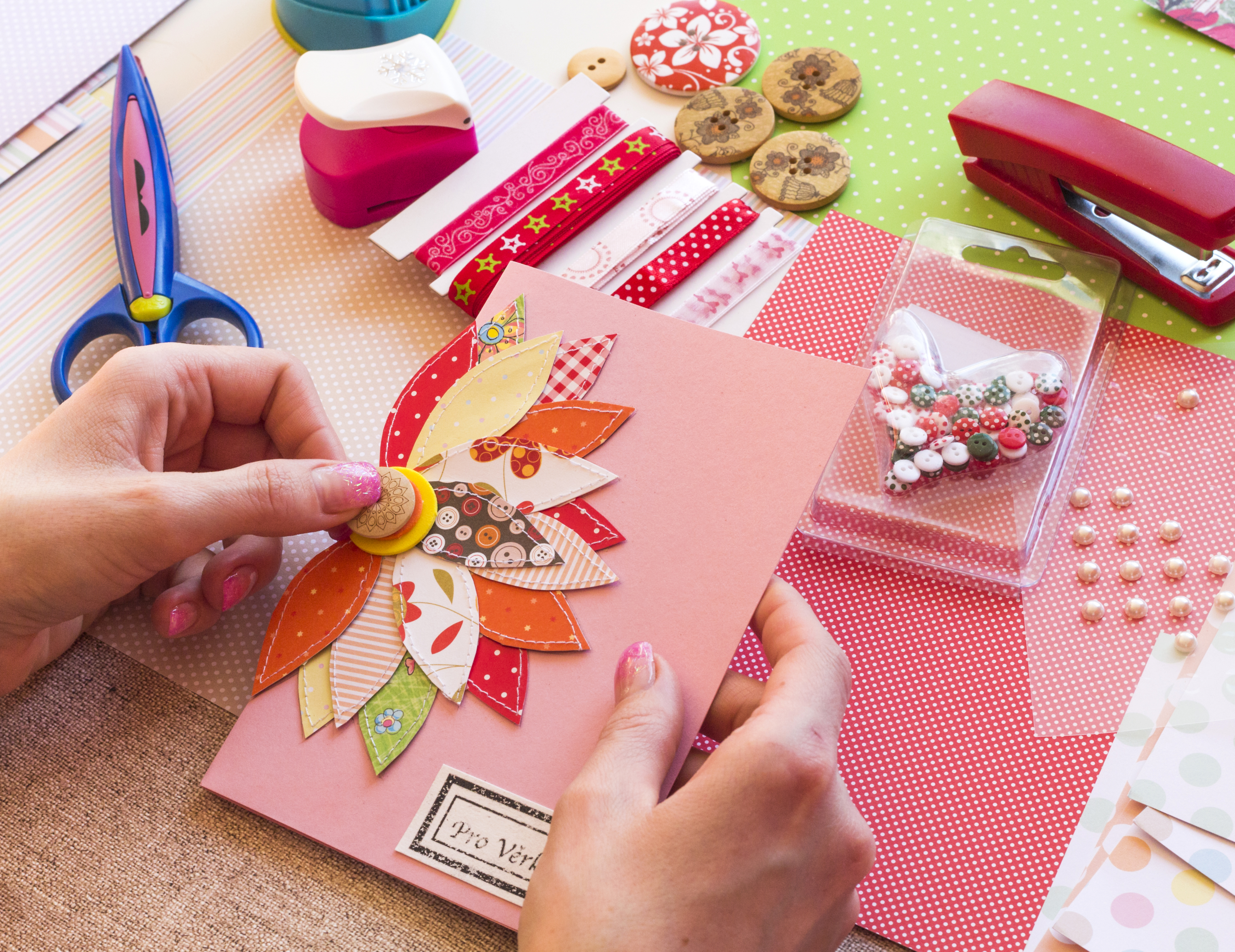 Photo of hands holding a handmade greeting card with cardmaking supplies in the background