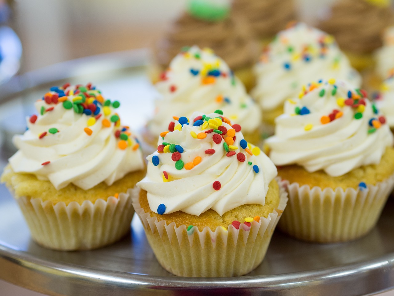 vanilla cupcakes, with white frosting and rainbow sprinkles