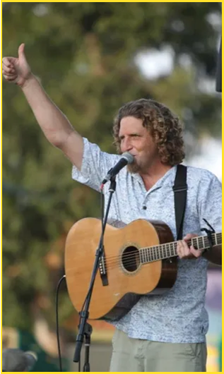 Man holding guitar and waving hand