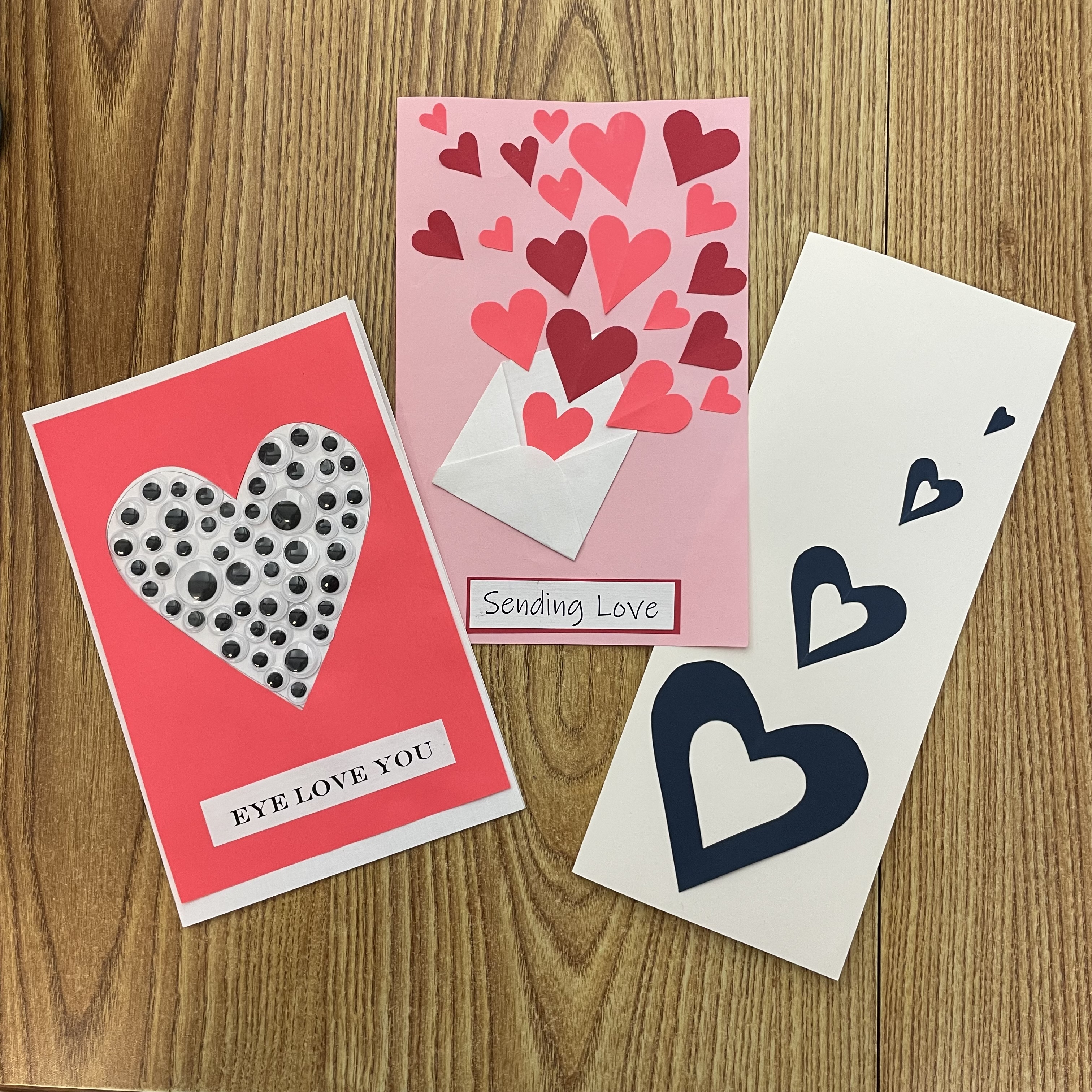 Three Valentine's cards show google eyes in a heart, reads, "Eye Love You", plus envelope with heart coming out, says "Sending Love", and third card has four blue hearts