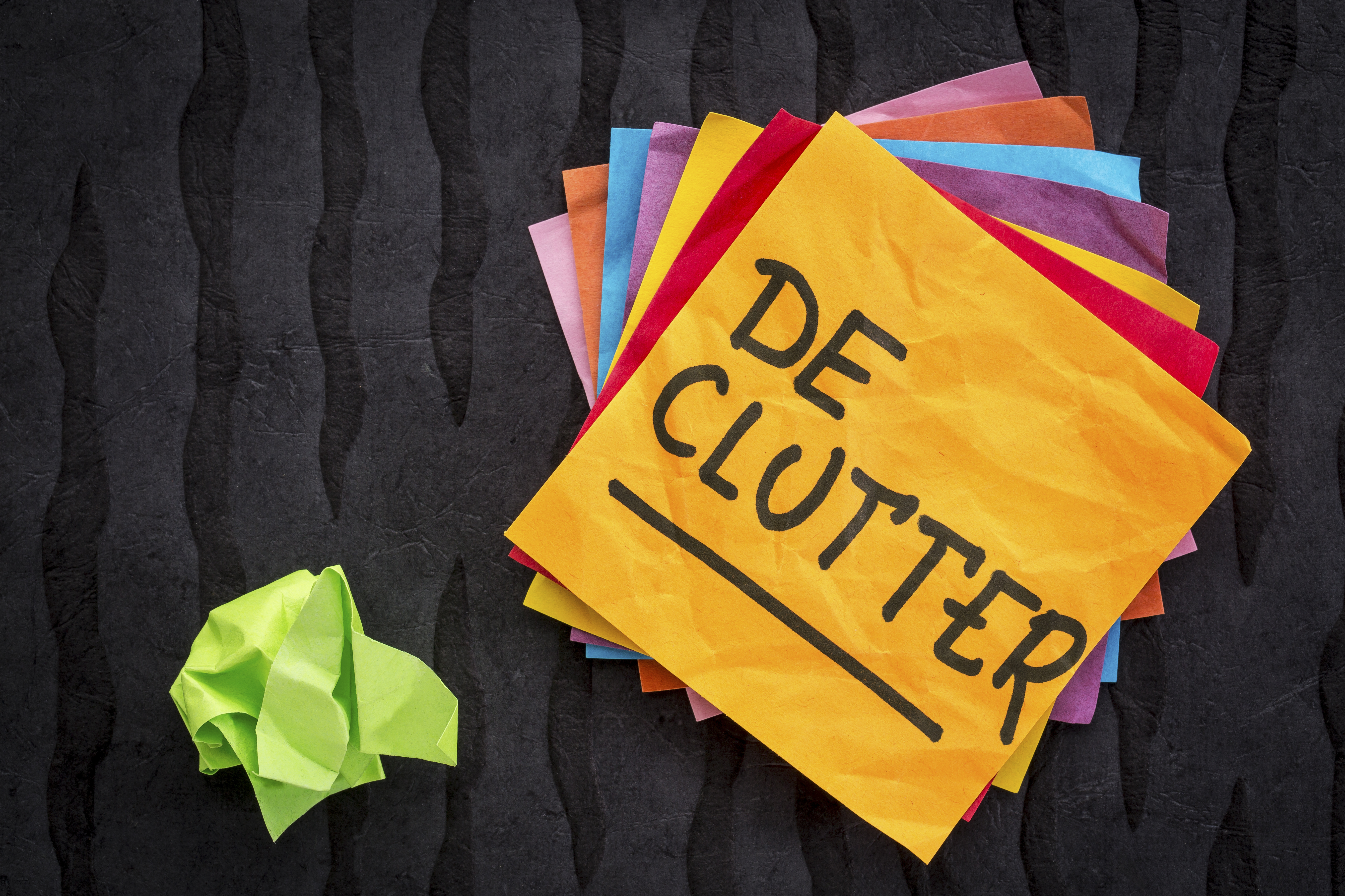 A colorful stack of sticky notes with "de-clutter" written on the top