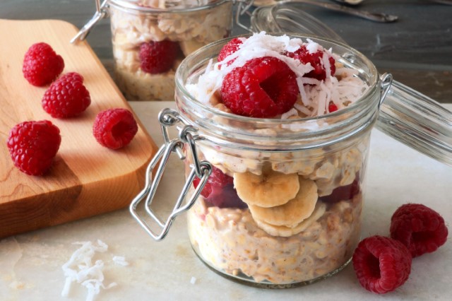 A mason jar of overnight oats with raspberries, bananas and coconut flakes.