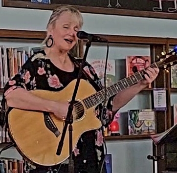 Photo of a woman holding a guitar and singing