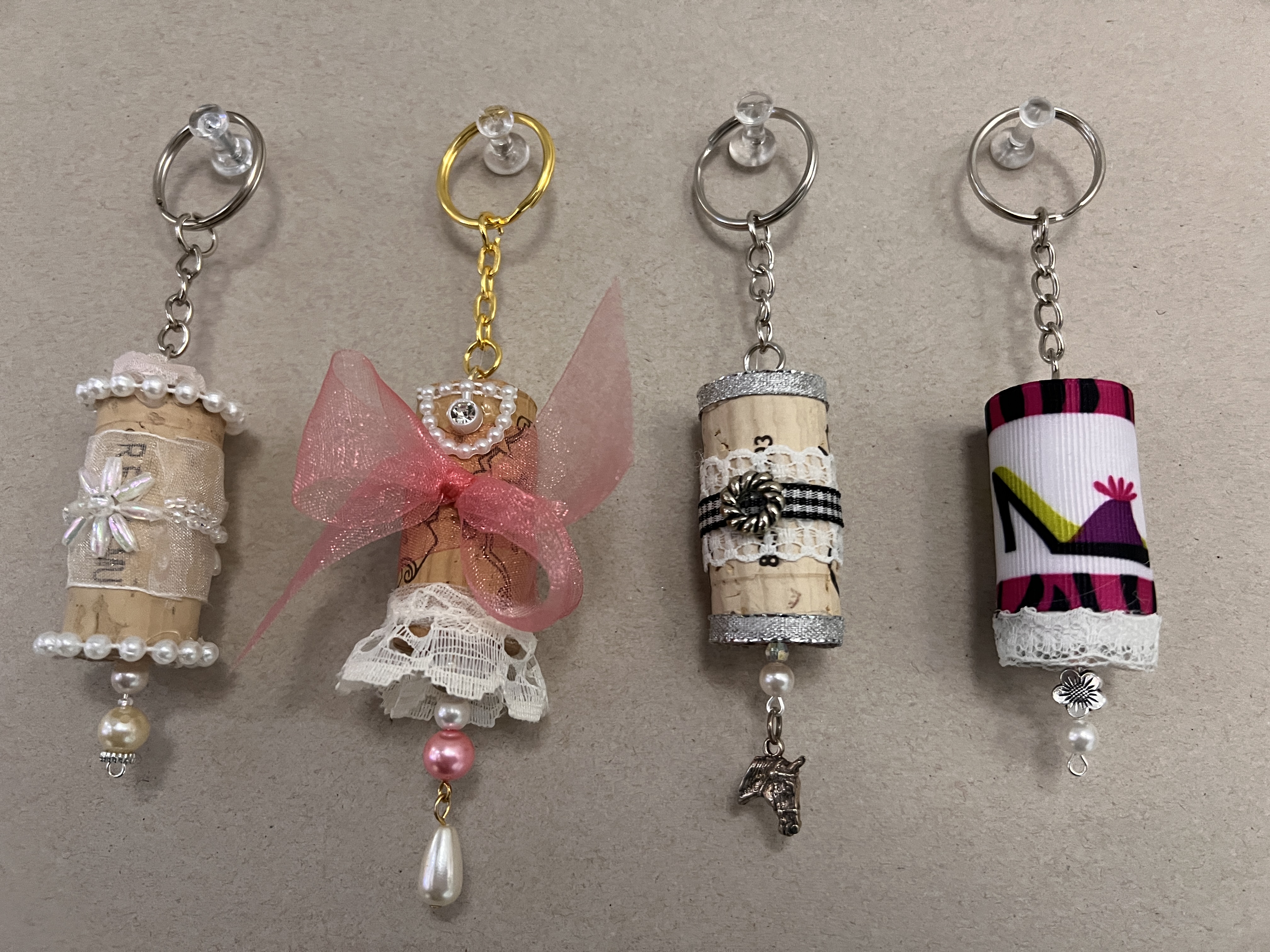 Four cork keychains decorated in whimsical designs