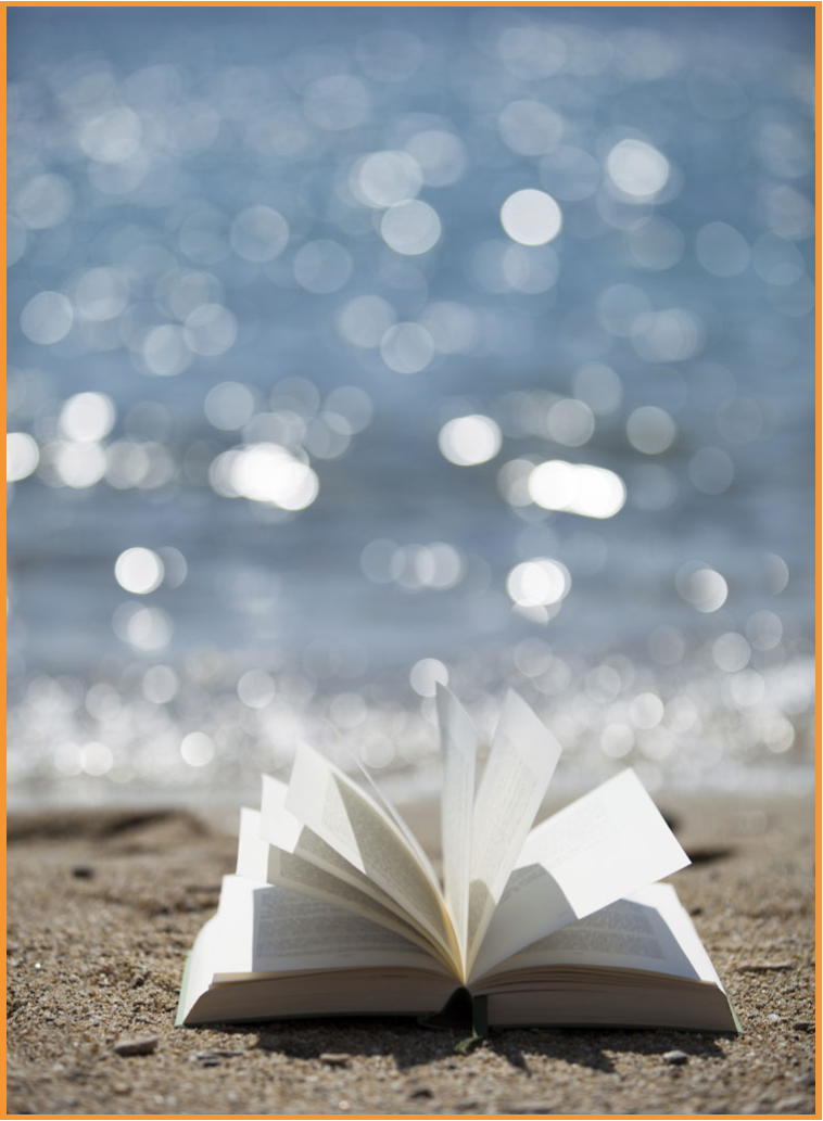 a book with pages open laying on a sandy beach with sparkling water in the background