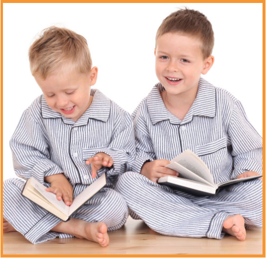 two young boys in blue striped PJs smiling and looking at books