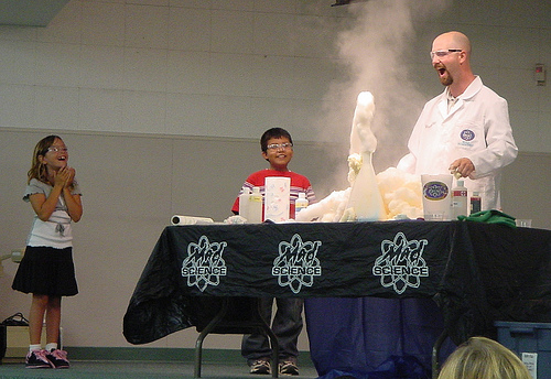 Scientist conducts experiment while two children watch.